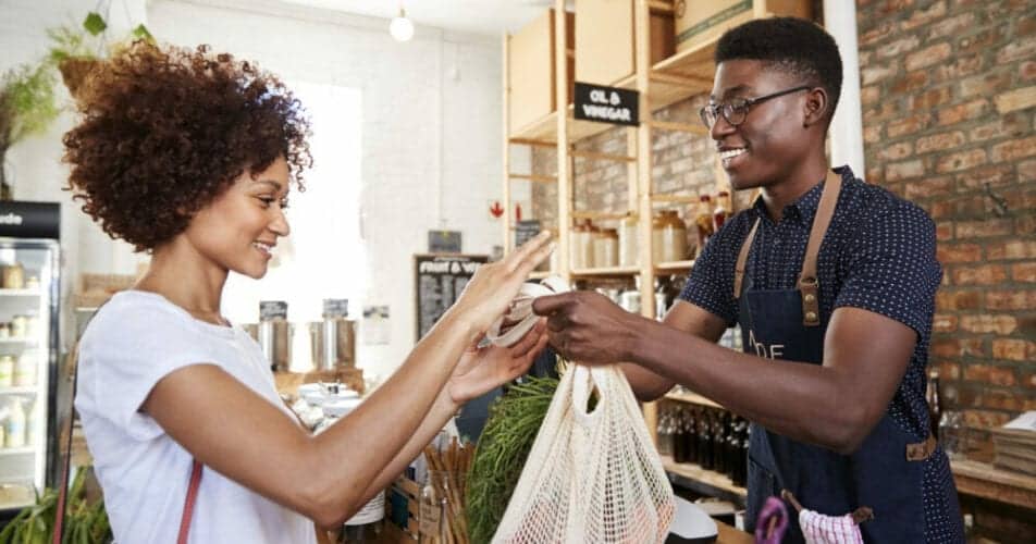Customer Paying For Shopping At Checkout Of Sustainable Plastic Free Grocery Store